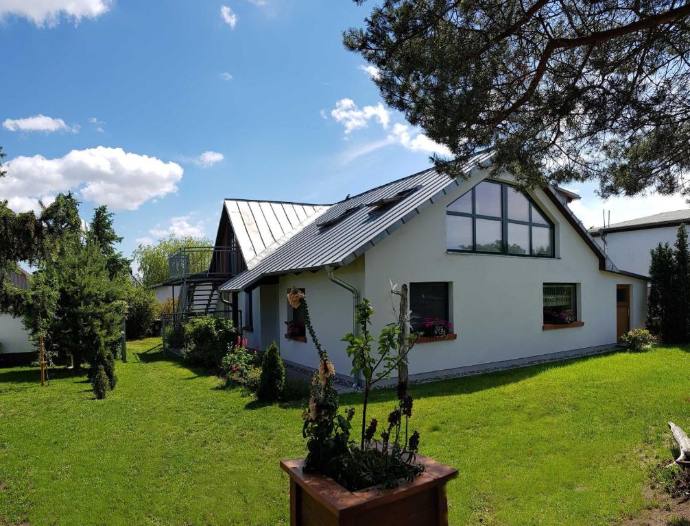 a white house with a tree in the yard at Ferienwohnung Graf Knurrhahn in Karlshagen