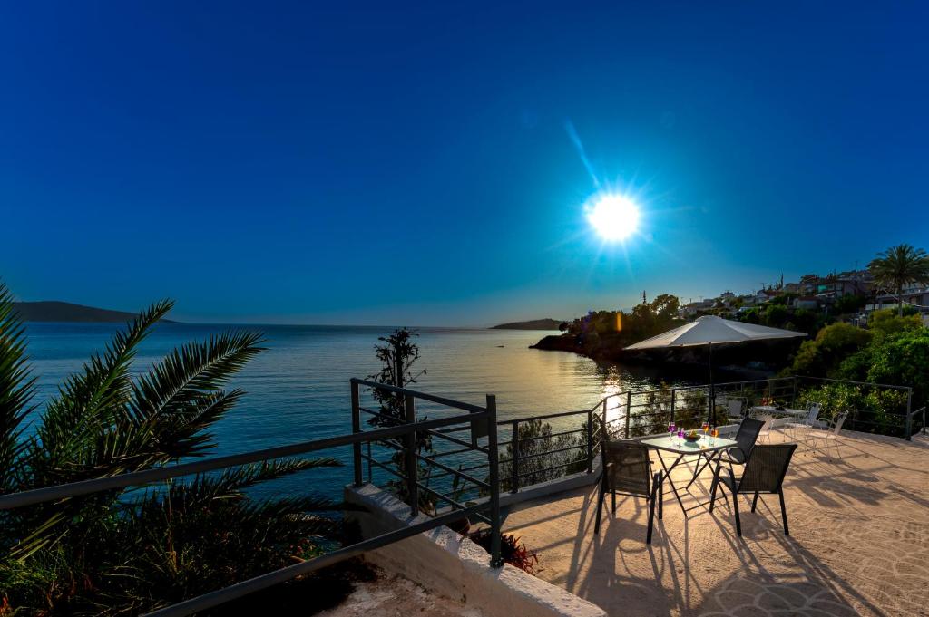 a table with chairs and an umbrella on the beach at Deep Blue Escape Villa Salamina in Áyios Yeóryios