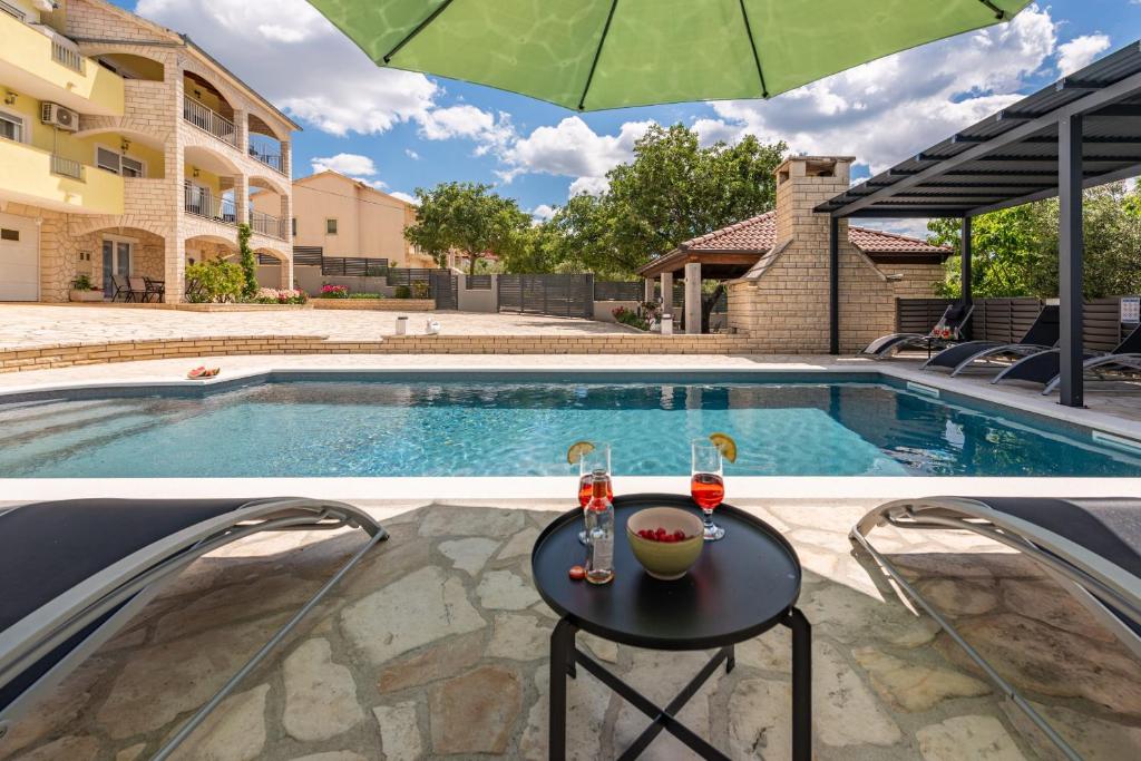 a swimming pool with a table and an umbrella at Villa Balen ZadarVillas in Lisičići