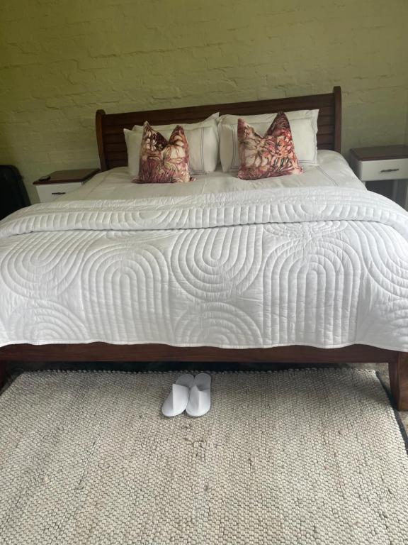 a bed with white sheets and pillows on it at Indaba tree lodge in Bulawayo