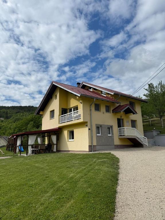 a large yellow house with a lawn in front of it at Apartman za odmor Plivska Jezera in Jajce