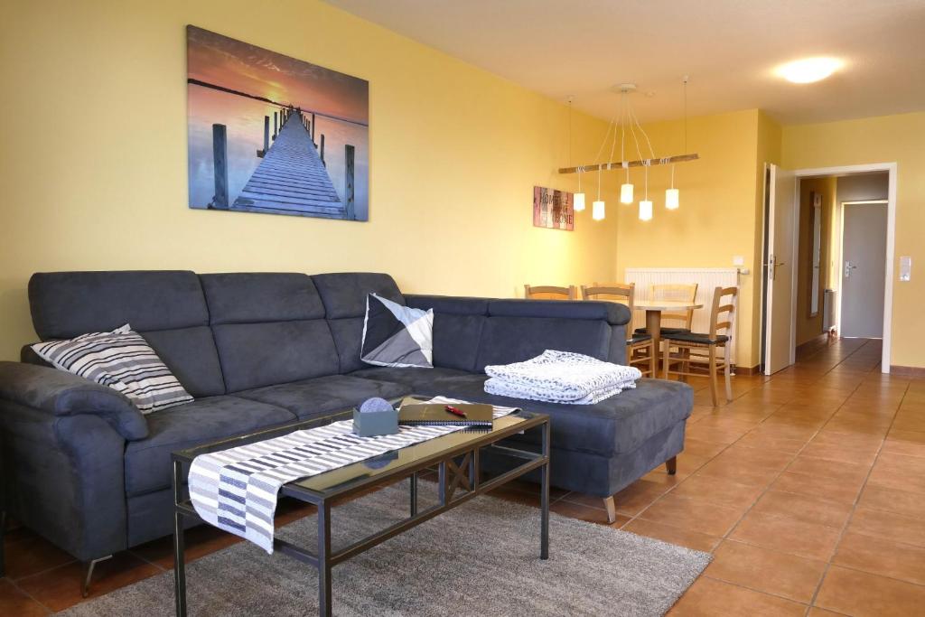 a living room with a blue couch and a table at Ferienwohnung Kranichglück in Neddesitz