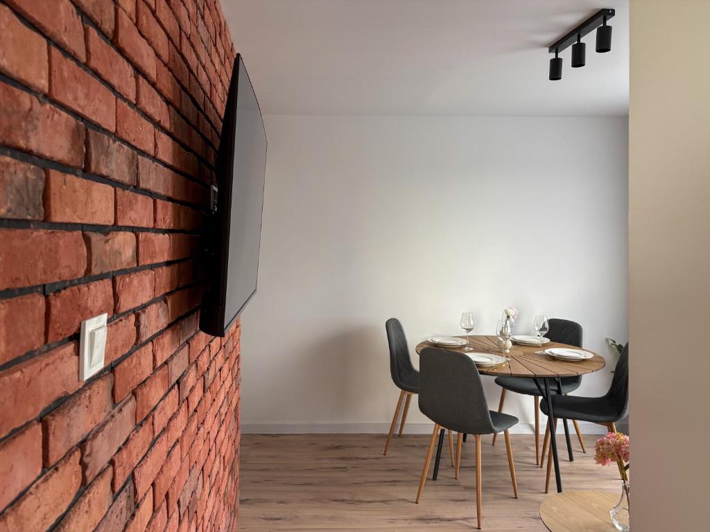 a dining room with a brick wall and a table and chairs at Apartament Bałandy 32 in Oświęcim