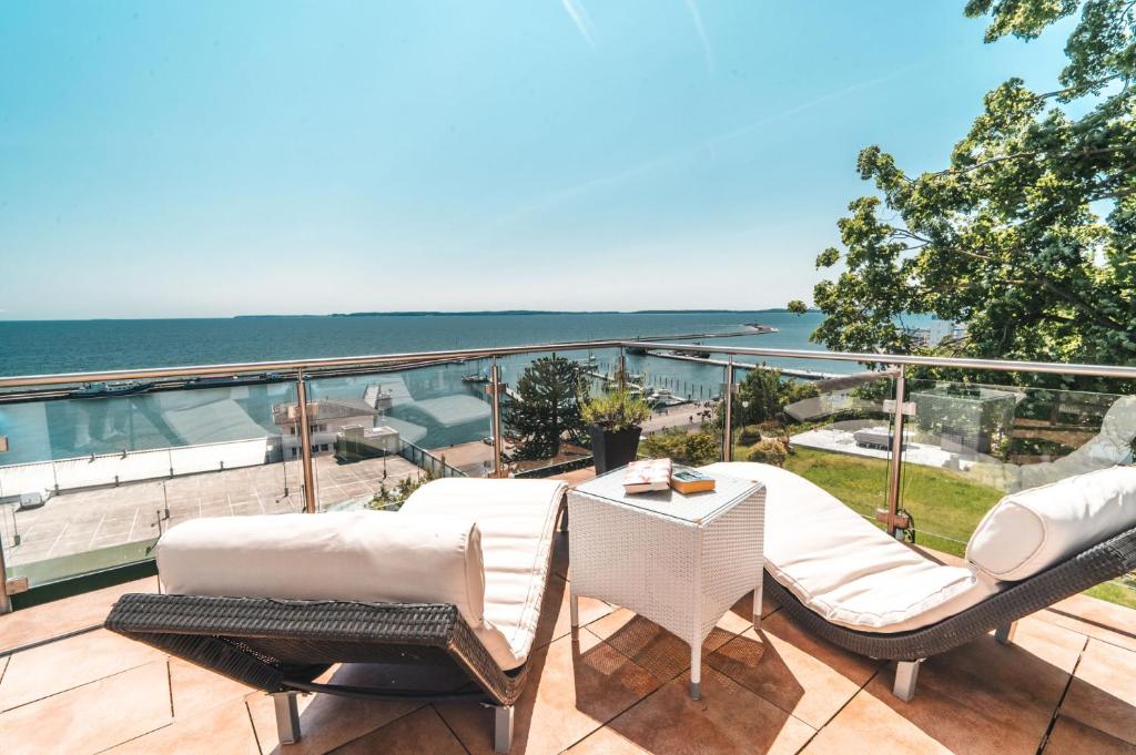 a balcony with chairs and a table and the ocean at Villa Friede Marie FeWo Ostseeweitblick in Sassnitz