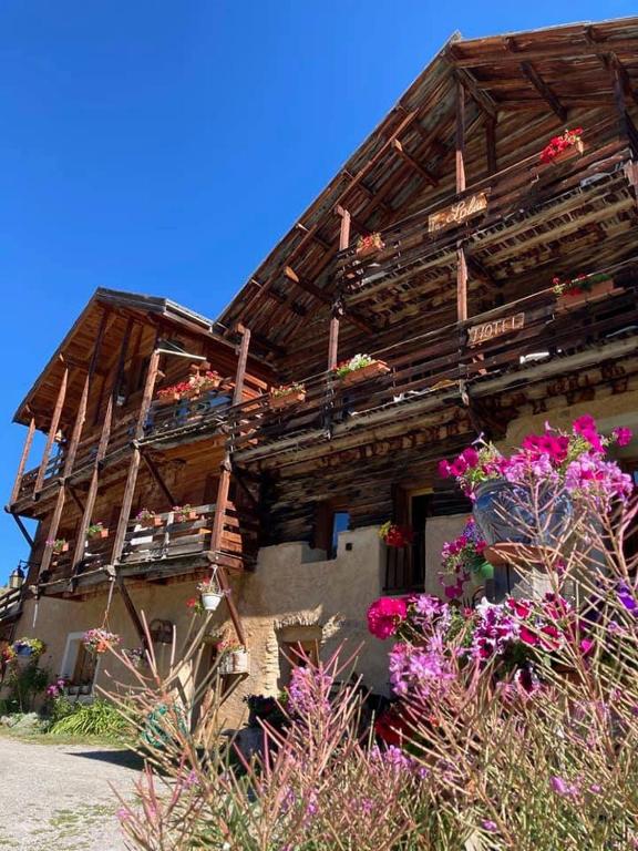 a wooden house with flowers in front of it at La Lobio in Molines-en-Queyras