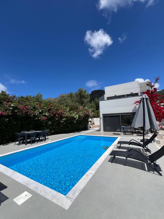 a swimming pool with two chairs and an umbrella at Villa Nicolas Plataria in Plataria