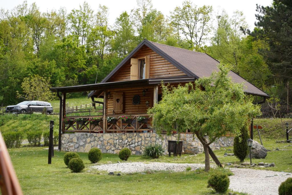 a log cabin with a porch and a tree at Brvnare Ljubojević in Kraljevo