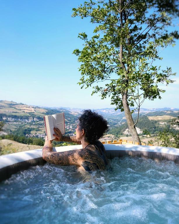 a woman in a bath tub reading a book at La Rock House BnB in Mercato Saraceno