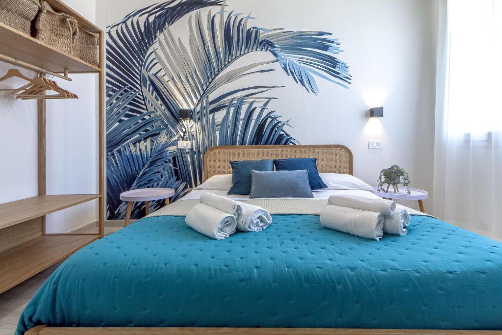 a bedroom with a blue bed with a mural of a palm tree at NURAS - Affittacamere L'Azzurra - Double bedrooms private bathroom and seaview solarium in Sorso
