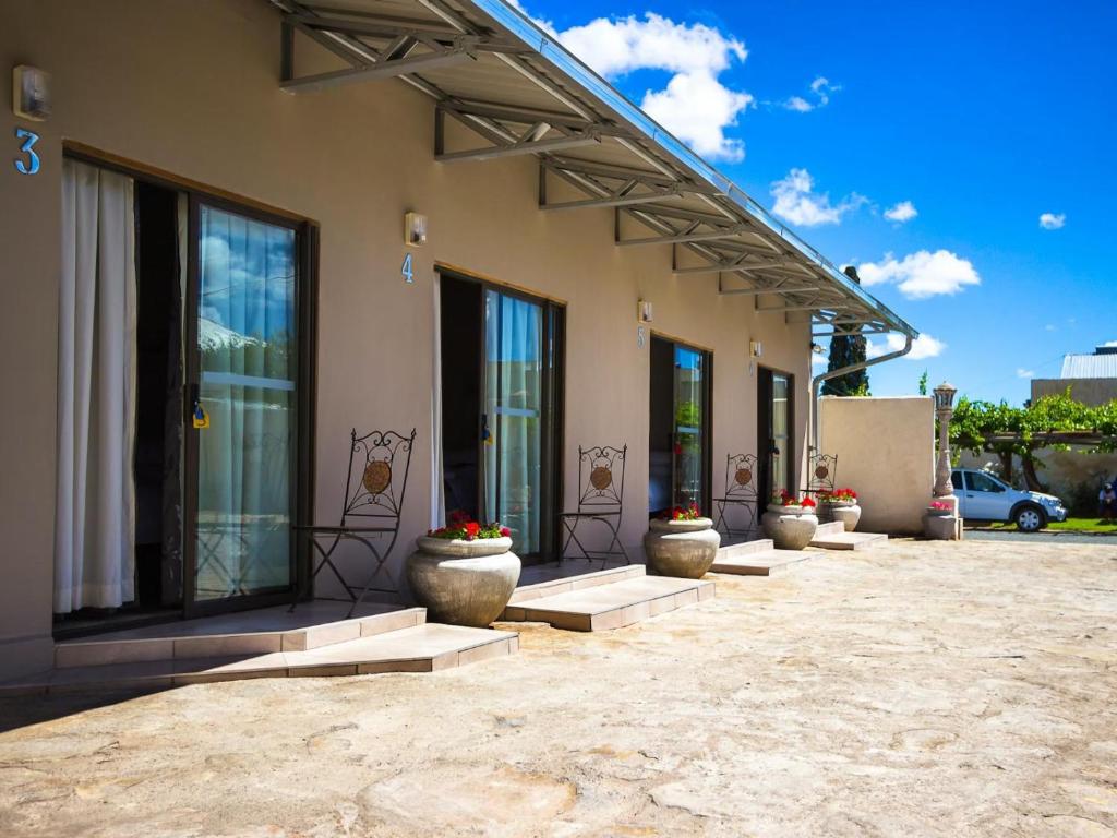a building with a row of flower pots in front of it at Hazeldene Accommodation in Colesberg