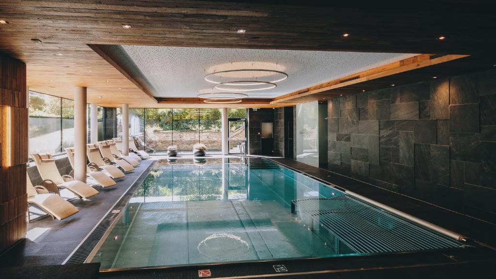 a swimming pool in a house with chairs around it at Hotel Kaprunerhof in Kaprun