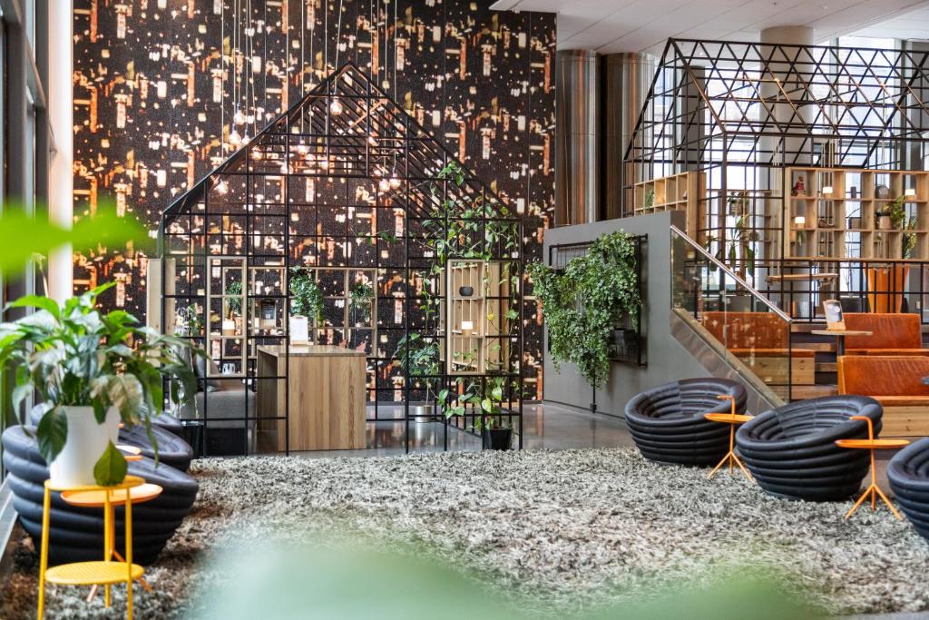 a lobby with tables and plants and a staircase at Comfort Hotel Union Brygge in Drammen