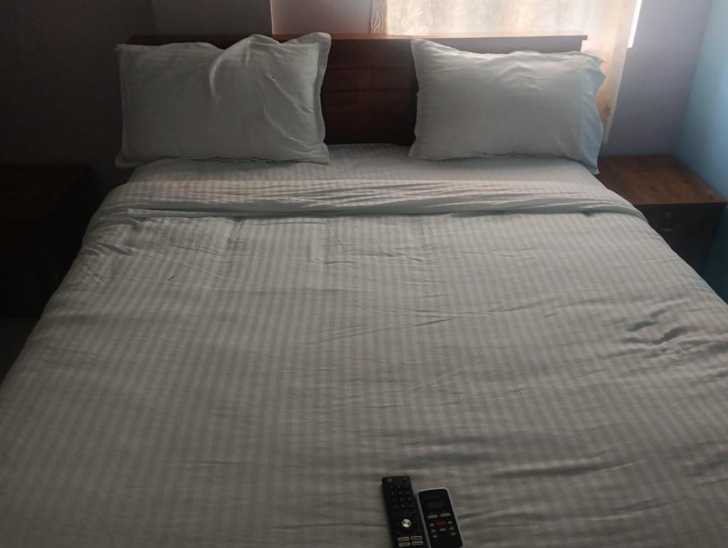 a bed with two pillows and a remote control on it at crown crest condos in Chengalpattu