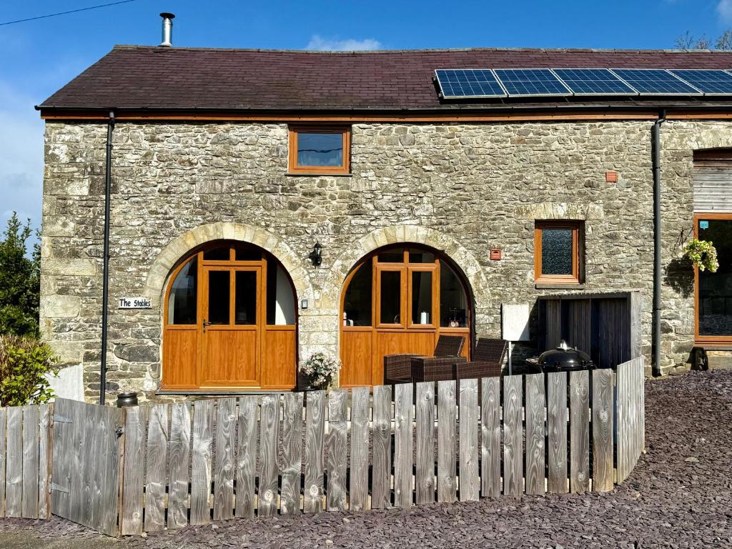 a stone house with wooden doors and a fence at The Stables in Llandysul