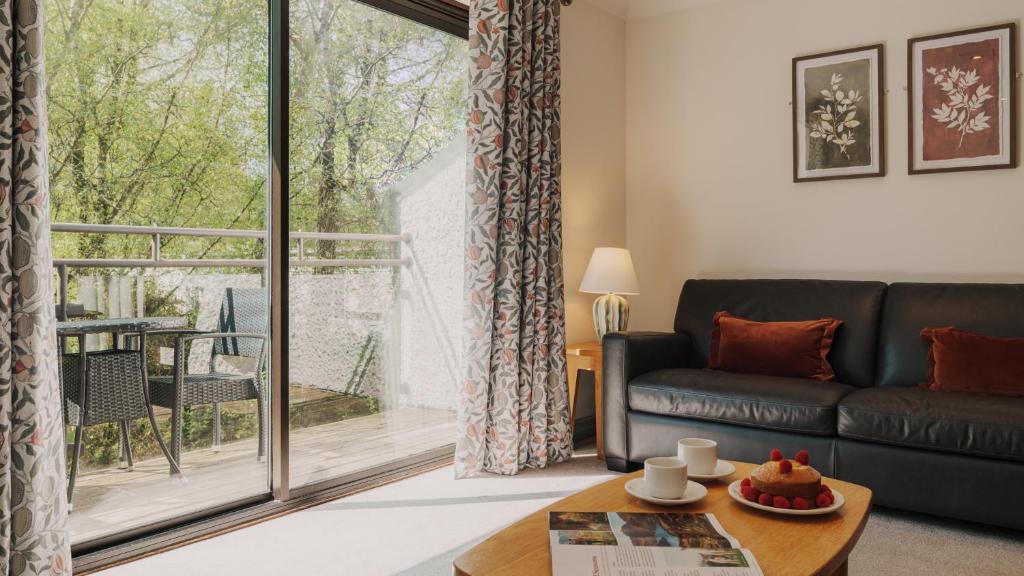a living room with a couch and a large window at Wansfell Cottage At Windermere Marina Village in Bowness-on-Windermere