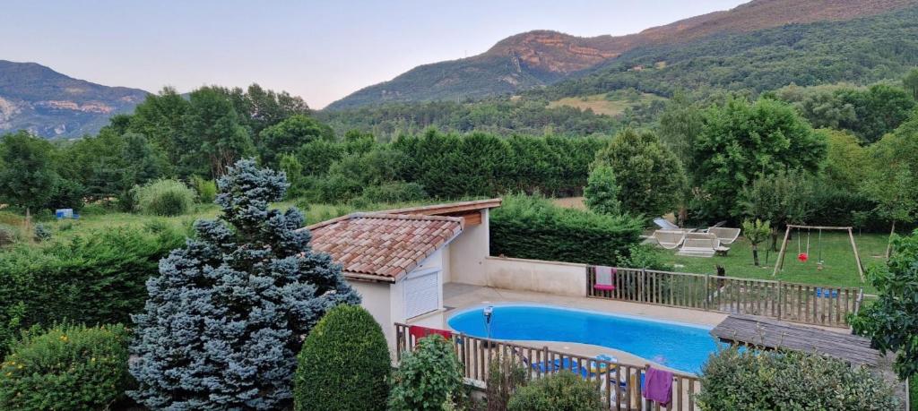 a villa with a swimming pool and mountains in the background at Gîte Le Devant De La Chaux in Pontaix