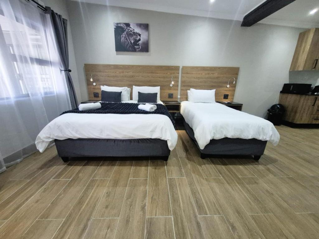 two beds in a large room with wooden floors at Casa Kruger Lodge in Phalaborwa