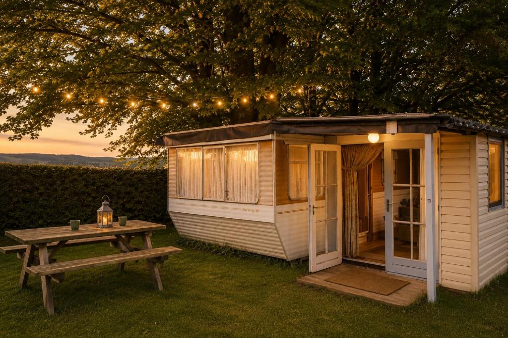 a tiny house with a picnic table and lights at Belgian GP 2026 Fast Access The Hilltop Lodge in Amblève