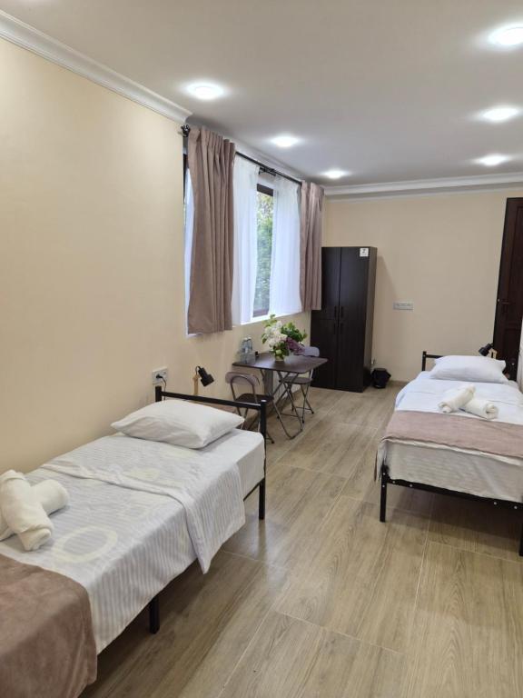 a bedroom with two beds and a table and a window at Noosh Ashnak guesthouse in Ashnak