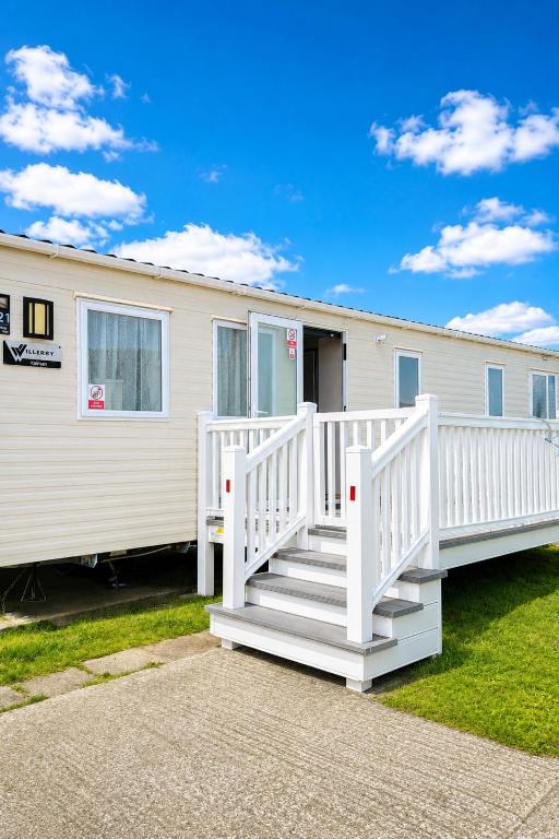 a mobile home with a white porch and stairs at Magic Caravan Camber Sands 221 in Camber