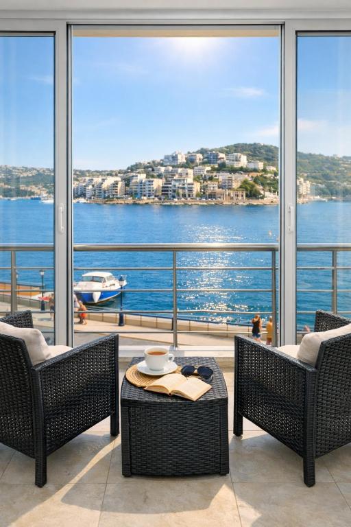 a balcony with two chairs and a table with a view of the water at The Terraces Seafront Getaway Malta 3 Bedroom Apartment in St. Paul's Bay