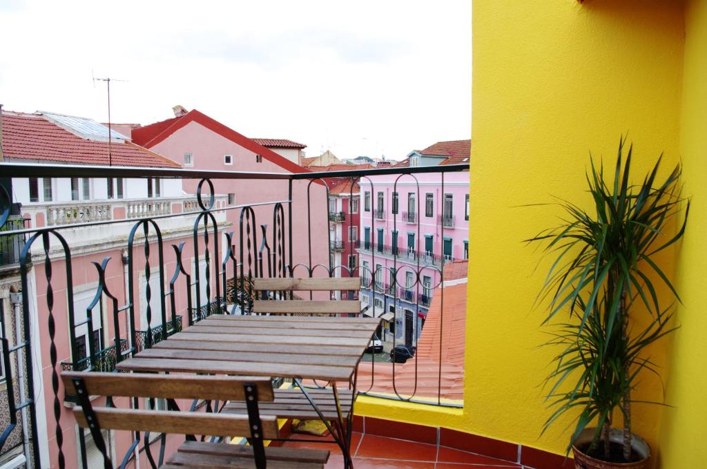 リスボンにあるLisbon Sloped Ceiling Apartmentの木製ベンチと黄色の壁が特徴のバルコニー