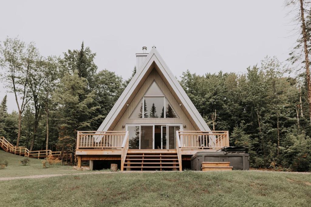 a small house with a gambrel roof on a field at Canadian Classic - Spa - Sauna - Fire - Forest in Val-David