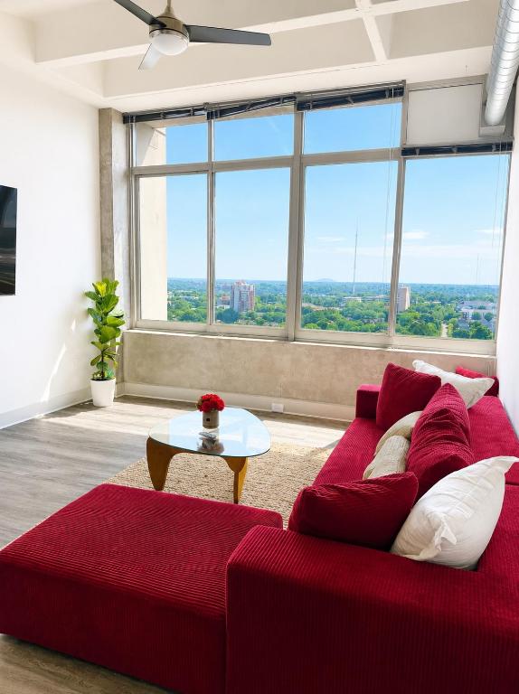 a red couch in a living room with a large window at Ember Sky Penthouse in Atlanta