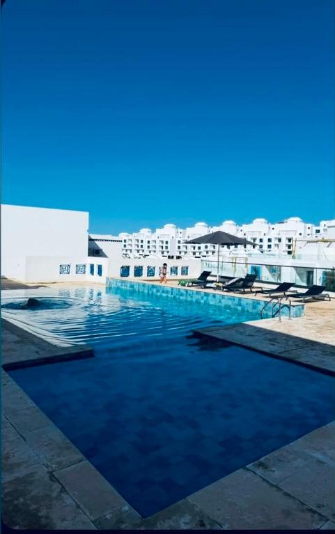 a large swimming pool with buildings in the background at Prestige Stay a Perla Méditerranée avec Picine au Centre Mdiq in M'diq