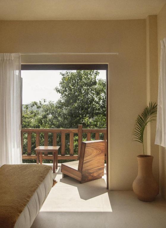 a bedroom with a balcony with a bed and a chair at Angelique's Boutique Spa & Suites in La Unión