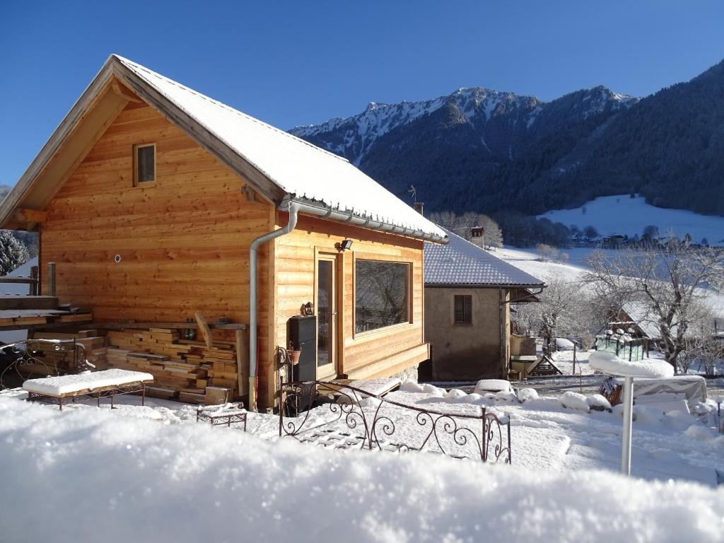 une cabane en rondins dans la neige avec des montagnes en arrière-plan dans l'établissement Le ptit Tavalan, à Seythenex