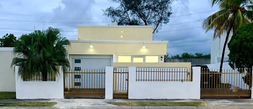 a yellow house with a white fence and a gate at Nice and Cozy House in the Greater Ponce Area in Ponce