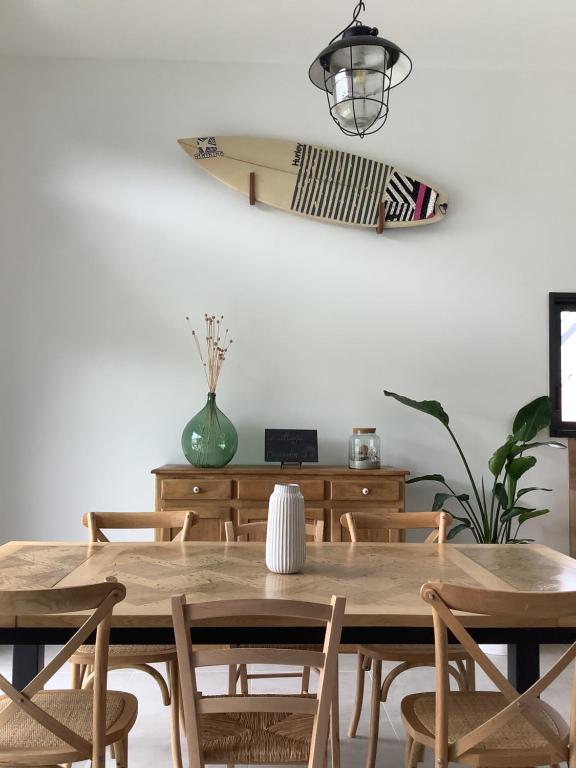 a dining room with a table and a surfboard on the wall at Le Cottage Bigouden in Combrit