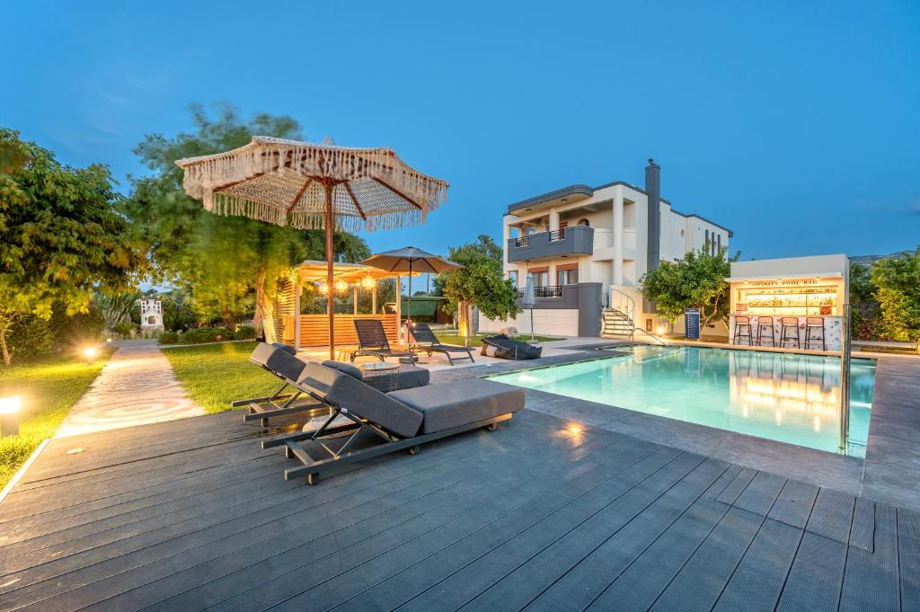 a pool with lounge chairs and an umbrella next to a building at The Infinities - Premium Villa Alexandros in Kos