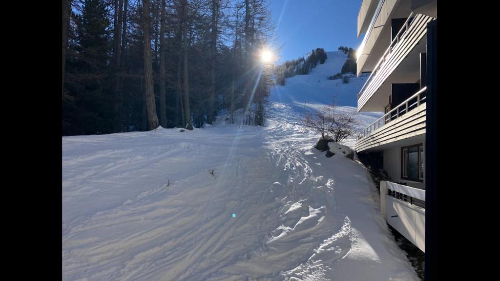 a snow covered ski slope next to a building at Studio pied de piste Pelvoux 2 in Vars