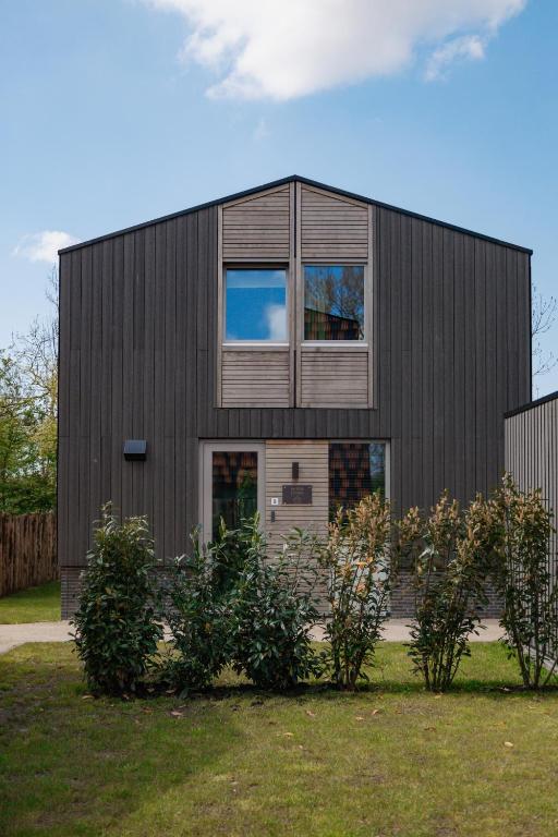 a black house with bushes in front of it at Parc La Dune Dutch Lodge in Warmenhuizen