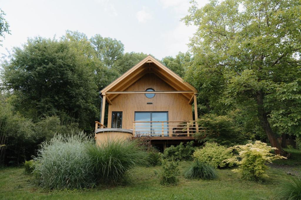 a small house with a large balcony in a garden at ZenZug, a vendégház in PerÅ‘csÃ©ny