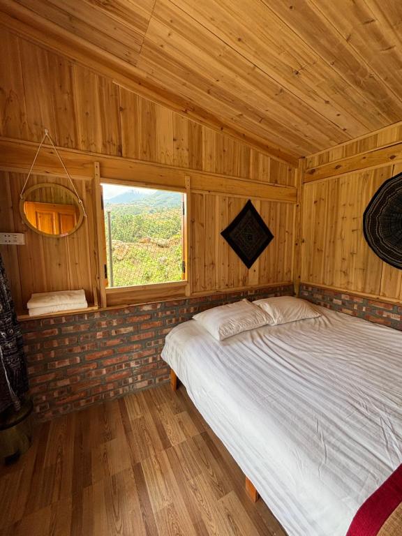 a bed in a wooden room with a window at Chacha's House in Sapa