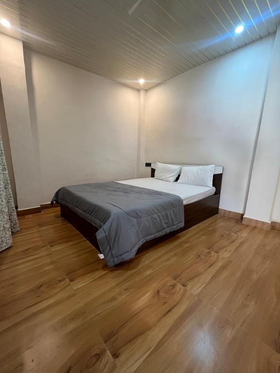 a bedroom with a bed and a wooden floor at The Courtyard Stay in Patna