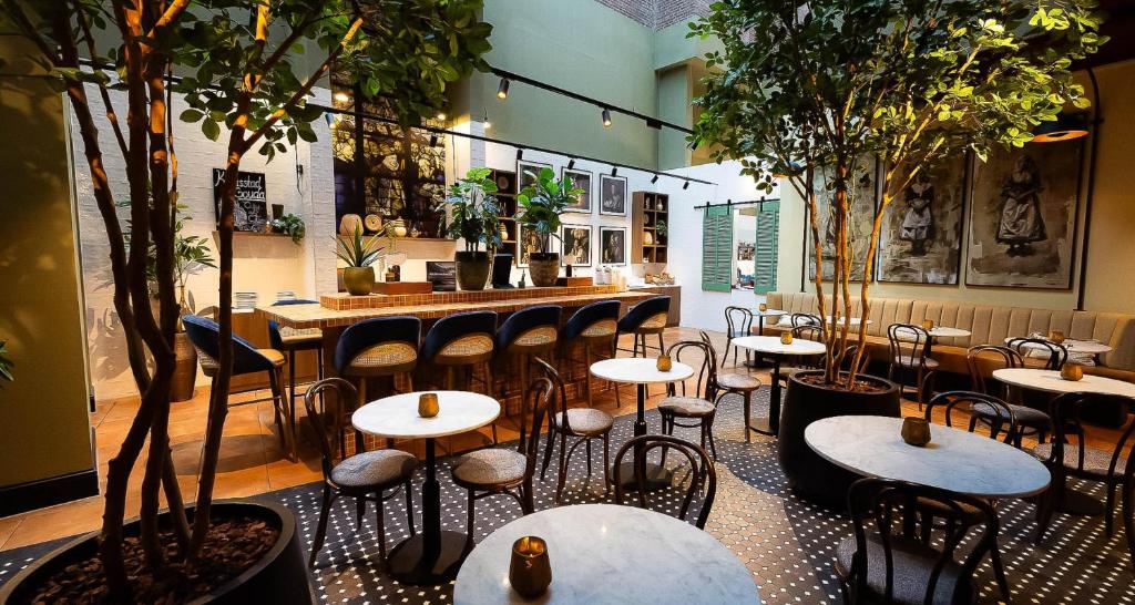 a restaurant with tables and chairs and trees at City Hotel Gouda, WorldHotels Crafted in Gouda