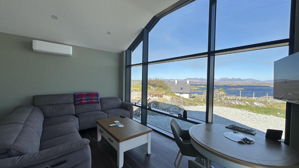 a living room with a couch and a table and a large window at Calla Retreat in Roundstone