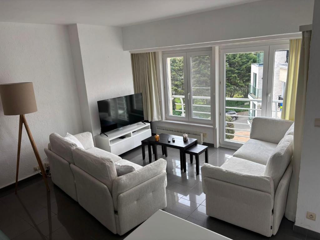 a living room with two chairs and a flat screen tv at Appartemment familial à Westende in Westende-Bad