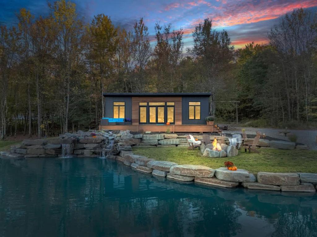 ein kleines Haus mit einem Teich davor in der Unterkunft Tiny House on a Waterfall at Private Tiny Lake in Brackney