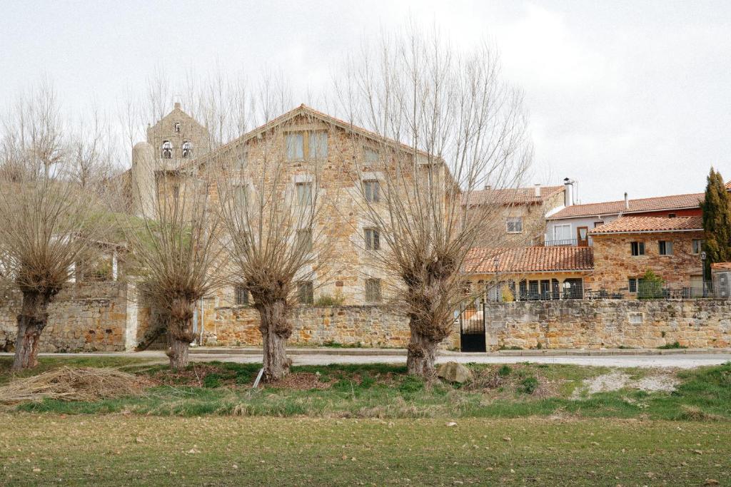 an old stone building with trees in front of it at Maison Barón de la Galleta B&B in Quintanilla las Torres