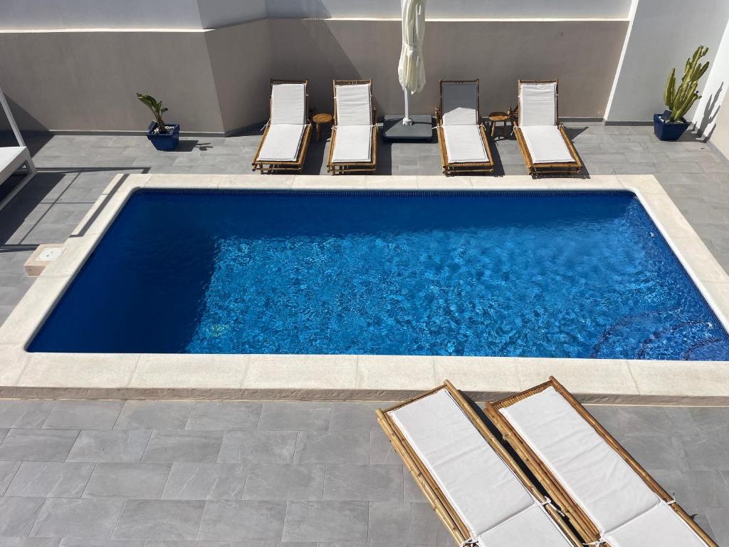 a pool with chaise lounge chairs and a swimming pool at Casa Bonic -Sunset Seaview in Sant Josep de sa Talaia
