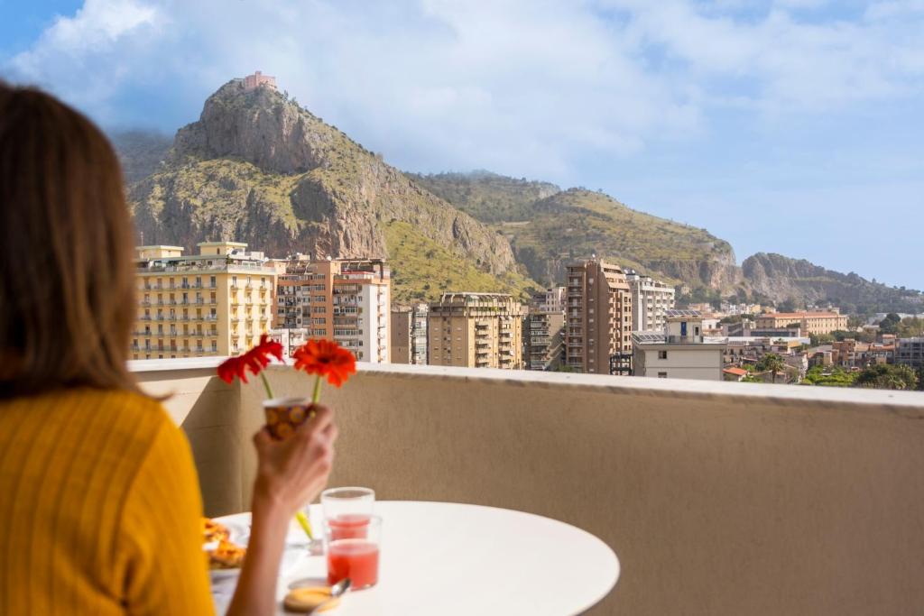 a woman sitting at a table with a vase with flowers at Marbela Apartments & Suites in Palermo