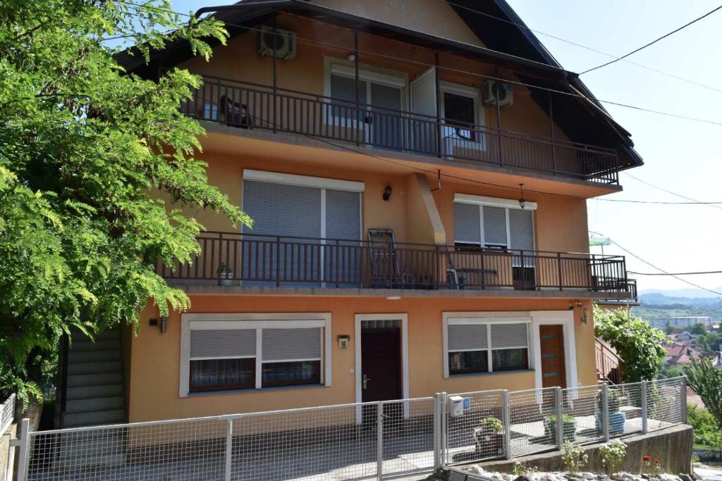 an orange house with a balcony and a fence at Apartments Mensa in Tuzla