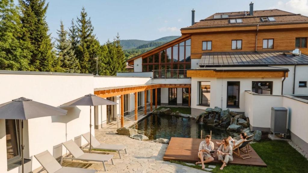 three women sitting on a deck in front of a house at Hotel Horal in Rožnov pod Radhoštěm