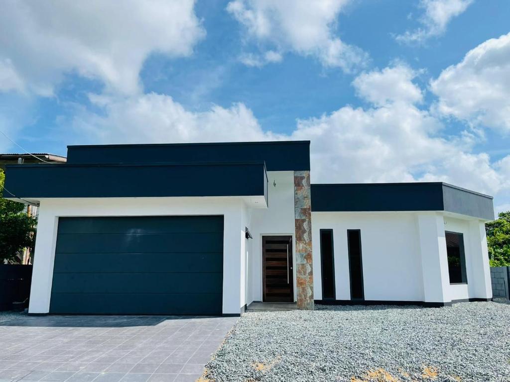 ein weißes Haus mit blauem Dach und einer Garage in der Unterkunft Aurelia in Paramaribo