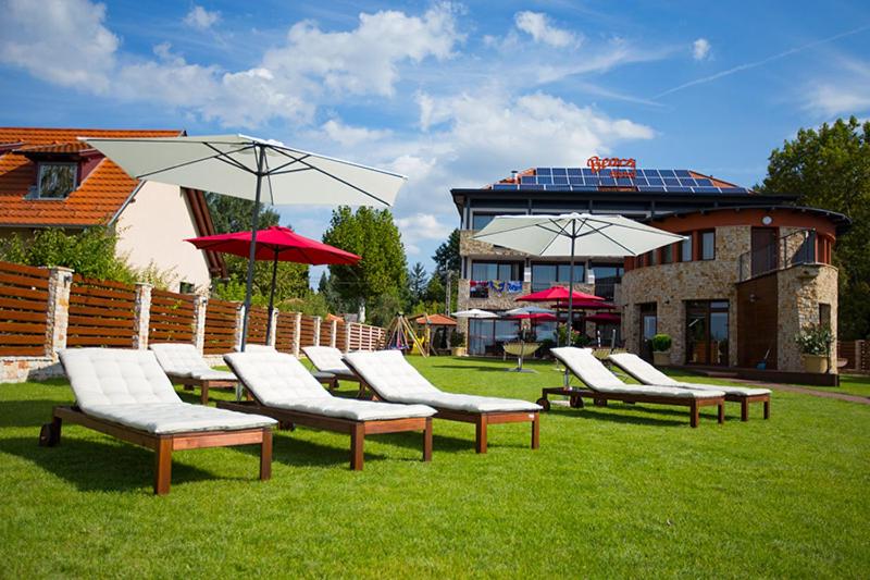 a group of lounge chairs and umbrellas on the grass at Pole Position Beach Hotel in Balatonszárszó